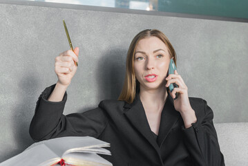 Young woman making notes and talking on phone.
