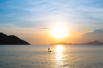 Silhouette of Stand Up Paddleboarder With Dog at Sunset Over Calm Sea