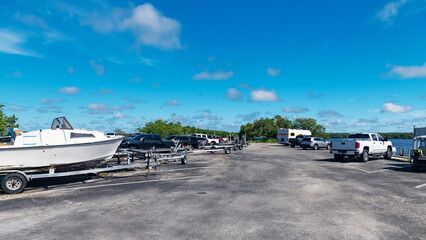 Boats on trailers parked near waterfront under blue sky on a calm sunny summer day © kosoff