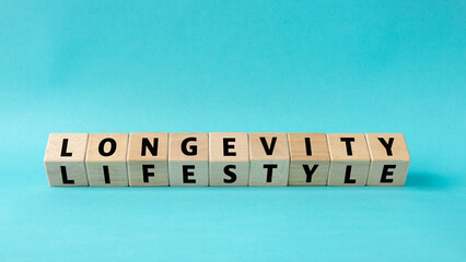 longevity and lifestyle. Wooden blocks reveal the text. Concept. The impact of lifestyle on longevity. Eating habits, positive attitude, social relationships, and physical activity. Blue background
