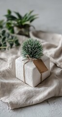 Small white gift box with a sprig, tied with twine, on a light beige linen cloth