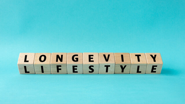 longevity and lifestyle. Wooden blocks reveal the text. Concept. The impact of lifestyle on longevity. Eating habits, positive attitude, social relationships, and physical activity. Blue background