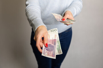 Płatność got&oacute;wką. Kobieta wyciąga rękę, w kt&oacute;rej trzyma pieniądze. Zbliżenie na dłonie