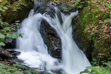 Fototapeta premium Long exposure of a waterfall on the East Lyn river flowing through the woods at Watersmeet in Exmoor National Park