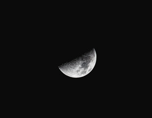 High-resolution photograph of a detailed waxing moon with visible craters and texture, isolated against a deep black night sky. Ideal for astronomy, science, space or background use. © Roland