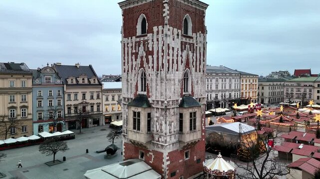 Cinematic drone shot rising past the historic Town Hall Tower over Krakow's empty Rynek Gł&oacute;wny (Main Market Square) during a peaceful winter sunrise.