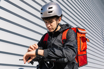 Young delivery rider with electric scooter and helmet