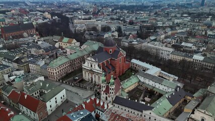 Cinematic aerial orbit shot circling the magnificent Baroque facade of Saints Peter and Paul Church in historic Krakow Old Town, Poland, during a cold winter day.