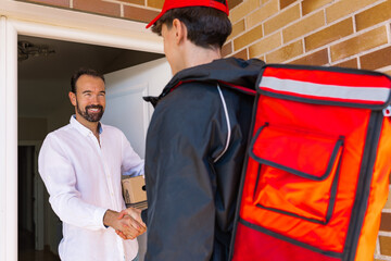Delivery boy handing package to smiling customer