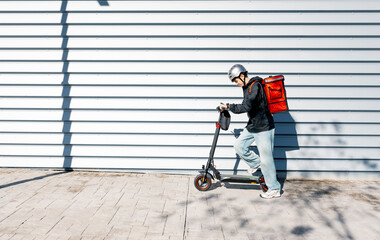 Young delivery boy riding an electric scooter on street