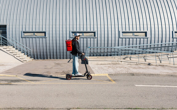 Young delivery boy on electric scooter by a building