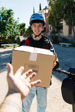Young delivery boy hands a package to a customer