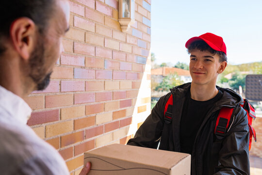 Young delivery boy handing package to customer