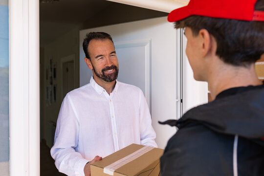 Delivery boy handing package to recipient at door