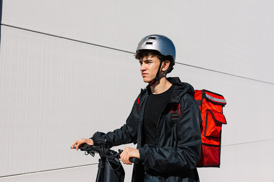 Young delivery boy riding electric scooter for deliveries