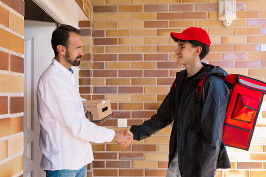 Young delivery boy hands package to man at door