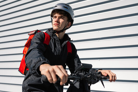 Young urban delivery boy on electric scooter outdoors