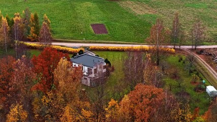 Drone aerial landscape of a private town home on bushland acreage surrounded by colourful autumn tree foliage beside rural farming countryside and a main road Cēsis Latvia Europe outdoors nature