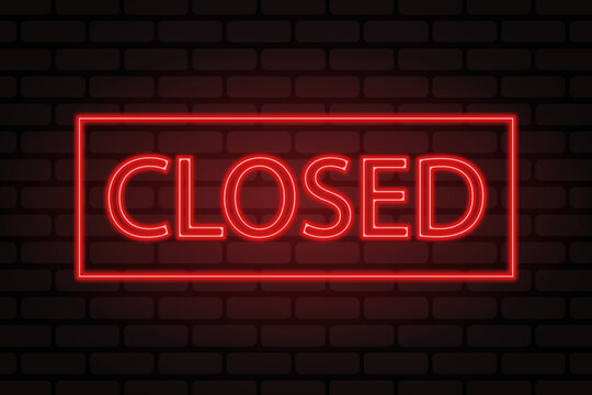 Red neon ''closed'' sign on brick wall background.