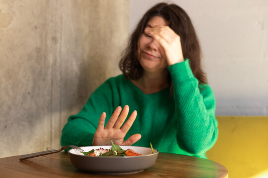 Woman expressing food aversion at a dining table