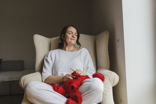 Woman enjoying knitting a cozy red sweater