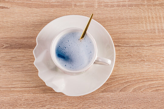 Blue matcha latte in white cup with golden spoon