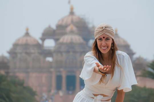Woman extends hand in front of Indian temple