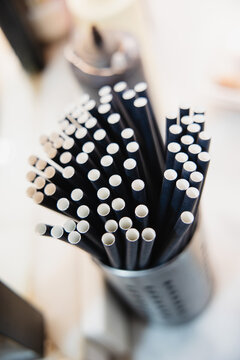 Black paper straws in metal holder on table