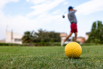 Golfer with yellow ball in foreground on green course