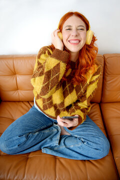 Woman enjoying music with headphones on sofa