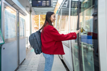 Woman in red coat boarding a tram during winter