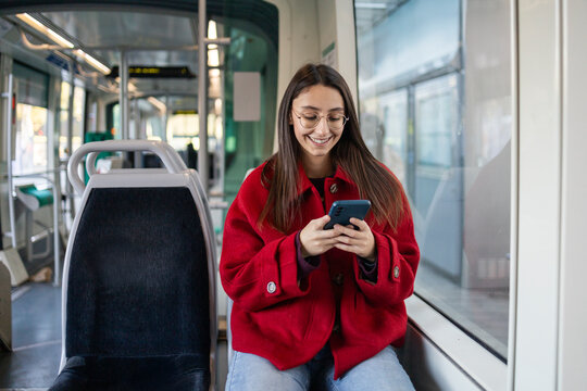 Woman in red coat using phone on public transport