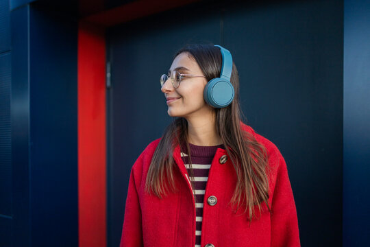Woman enjoying winter in a bright red coat with headphones