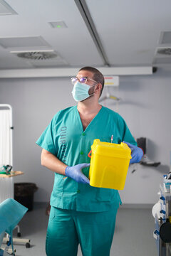 A healthcare worker handling surgical waste container in hospital