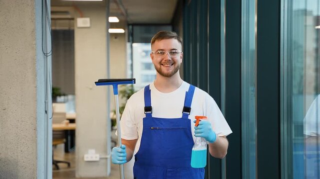 Professional window cleaner holding squeegee and smiling