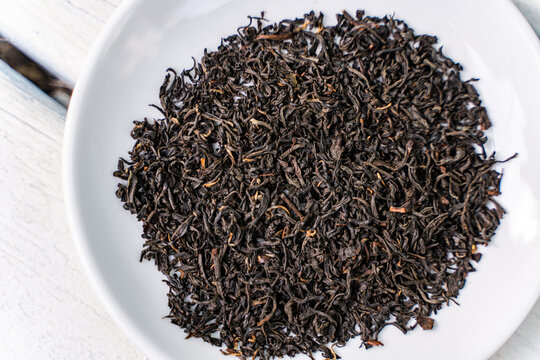 Aromatic black tea leaves on white ceramic plate