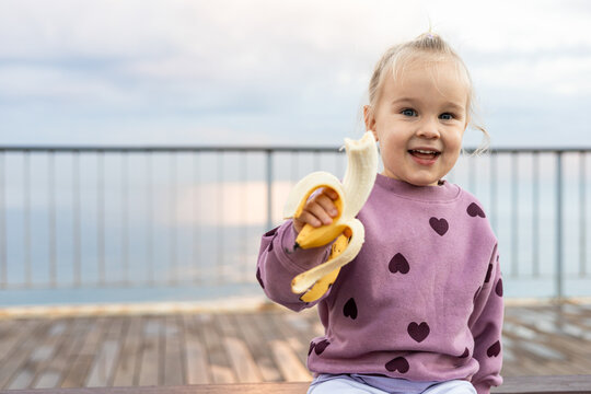 Toddler girl enjoying banana outdoors