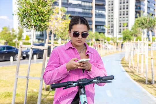 Young woman using rental scooter in urban environment