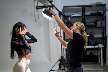 A female model with long hair poses confidently in a studio.