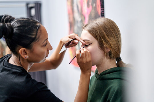 Makeup artist applying eyeliner to a model during a stylish photoshoot