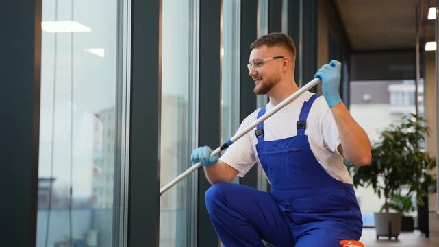 Professional janitor cleaning office window with squeegee
