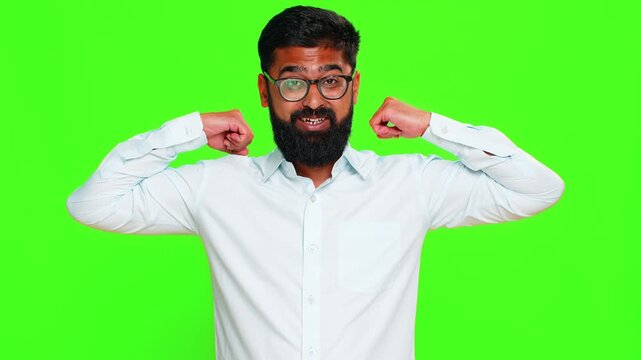 Indian man flexes arms shows muscles with confident smile, expressing physical strength, pride, motivation. Arabian guy isolated on green chroma key background showing power and self-assurance energy.