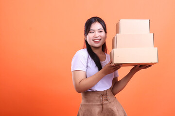 A cheerful young woman carries a stack of cardboard boxes with a smile, ready to deliver or move...
