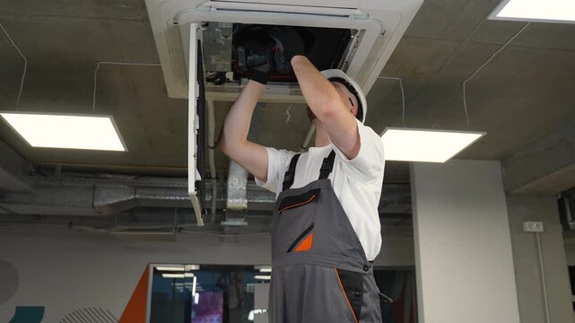 Technician repairing ceiling air conditioner ventilation system