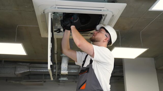 Hvac technician servicing ceiling cassette air conditioner unit