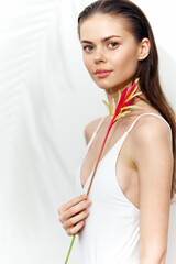 Young woman holding a vibrant flower, showcasing natural beauty and elegance in a minimalist setting.