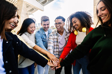 Happy multiracial friends showing unity by holding hands, enjoying time together in the city. Friendship and bonding concept.