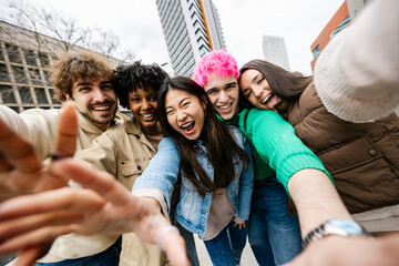 Multiracial group of young friends smiling while taking selfie. Excited students capturing fun moments outside. Youth lifestyle and friendship concept.