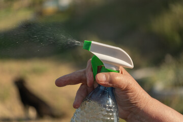 Hand using spray bottle outdoors, eco friendly home cleaning and garden plant care concept