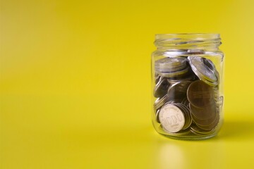 jar containing coins on yellow background